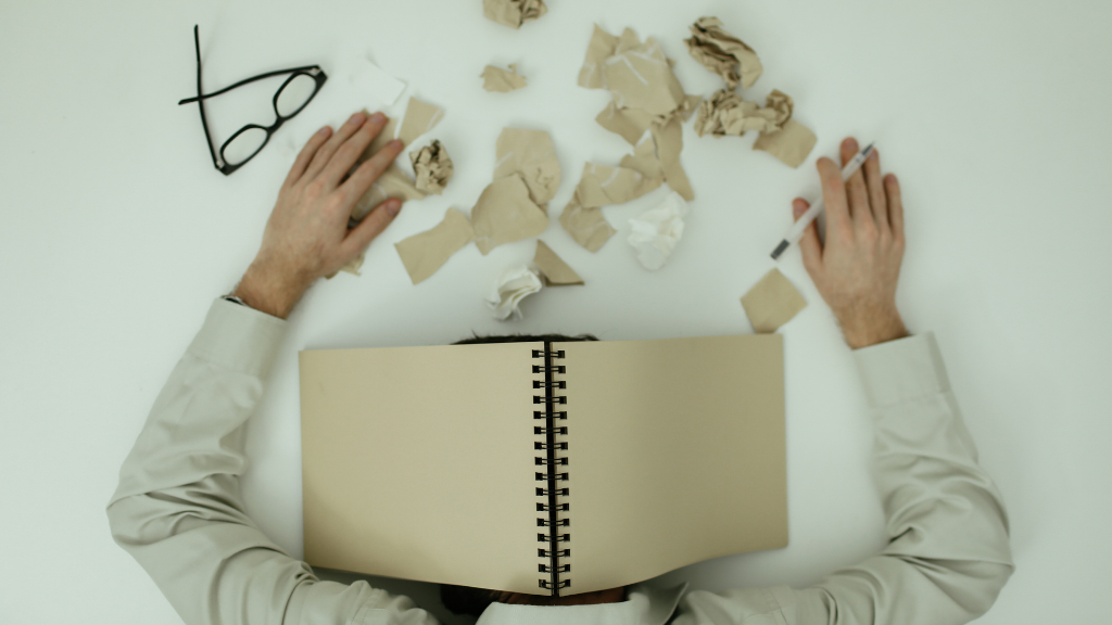 Erschöpfte Person am Schreibtisch mit Laptop Burnout