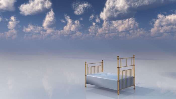Bild eines Bettes auf einem glatten Untergrund, im Hintergrund Schäfchenwolken