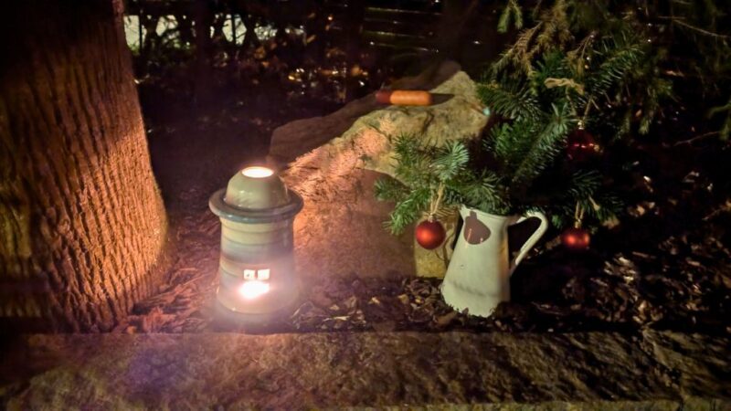 Grabstein, Licht und Blumen in einem Garten, Grab eines Hundes, Würstchen liegt auf dem Grabstein