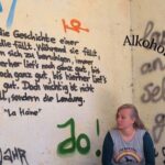 Frau hockt vor Wand in lost place, an der etwas geschrieben steht, Symbolbild für Artikel über Alkohol und ADHS