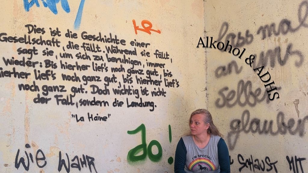 Frau hockt vor Wand in lost place, an der etwas geschrieben steht, Symbolbild für Artikel über Alkohol und ADHS